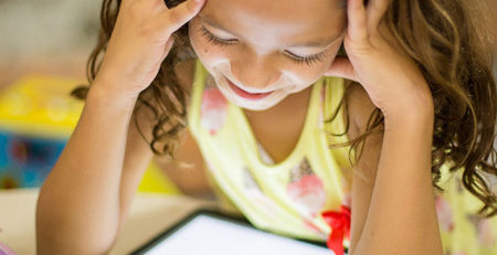 Child sat at desk online on a tablet.